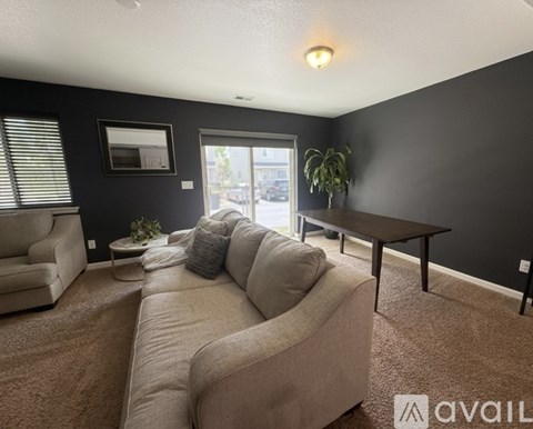 A living room with a beige couch and a brown carpet.