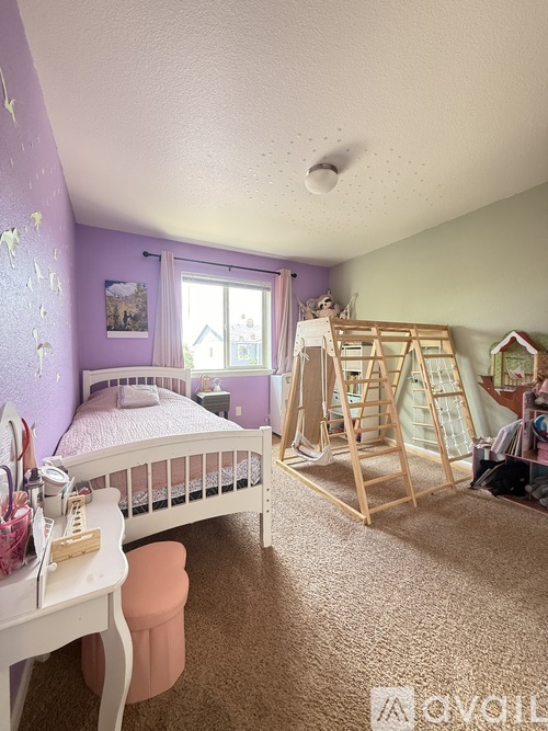 A child's bedroom with a white bed and a wooden playhouse.