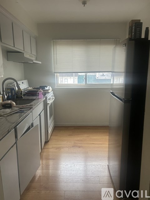 A kitchen with white cabinets and a black fridge.