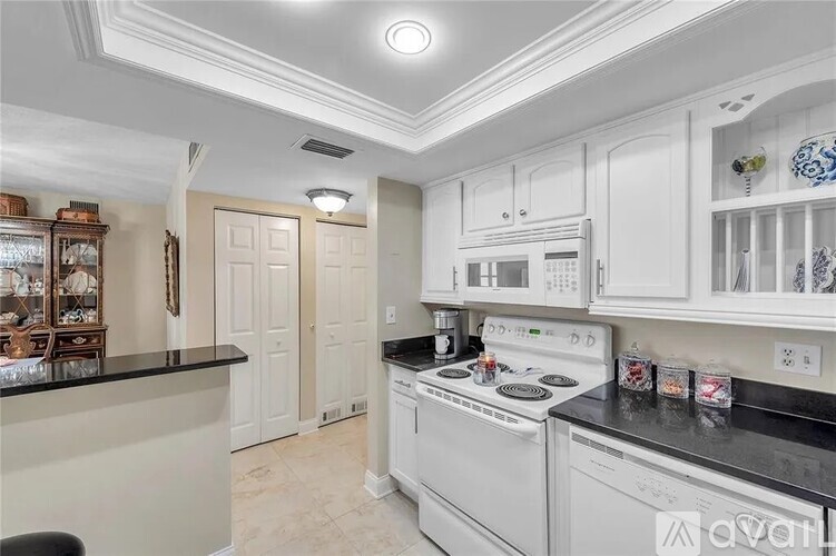 A kitchen with white cabinets and black countertops.