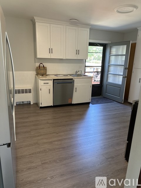 A kitchen with white cabinets and a wooden floor.
