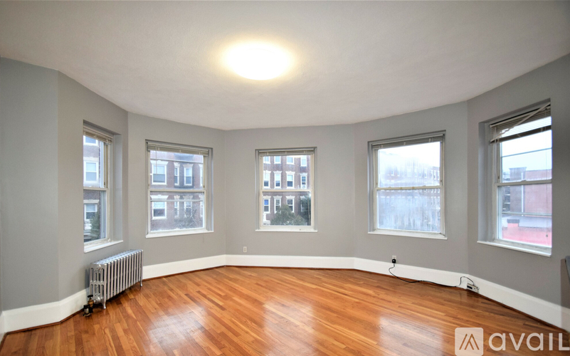 A room with wooden floors and three windows.