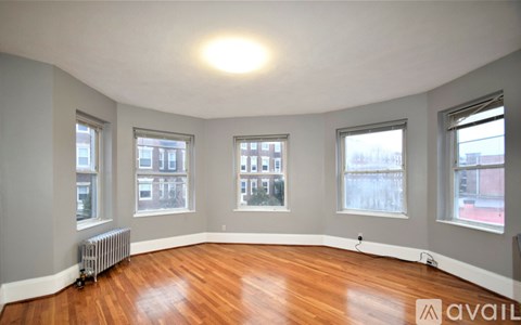 A room with wooden floors and three windows.