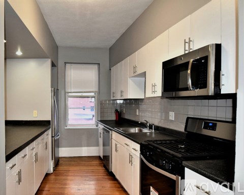 A kitchen with black countertops and white cabinets.