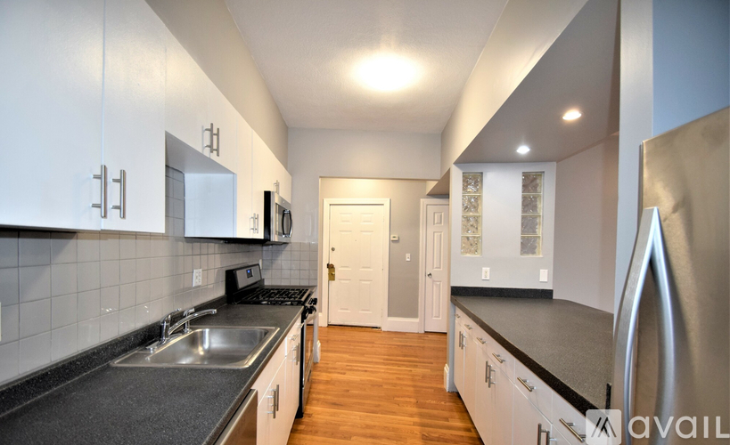 A kitchen with white cabinets and a black countertop.