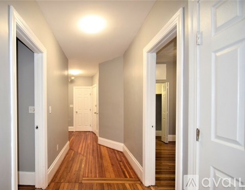 A hallway with wood floors and white walls.