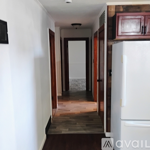 A hallway with a white door and a white refrigerator.