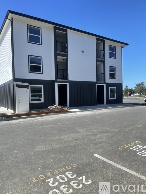 A white and black building with the words "AVAILABLE" written on the ground in front of it.