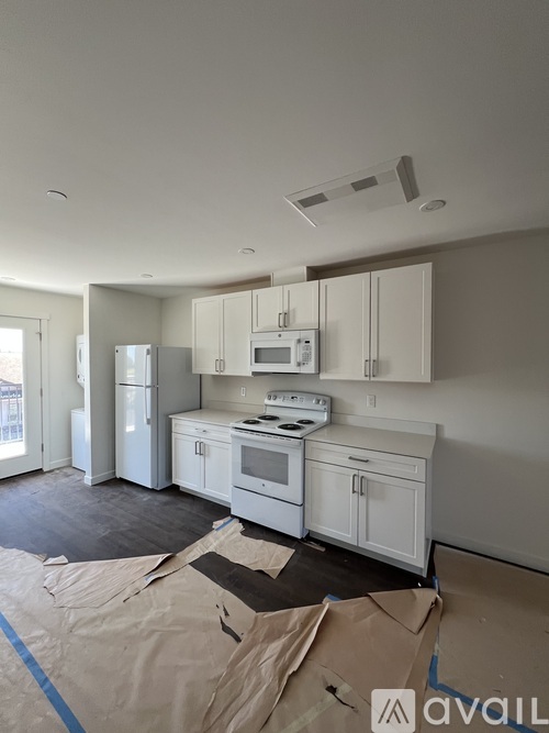 A kitchen with white cabinets and appliances is under construction.