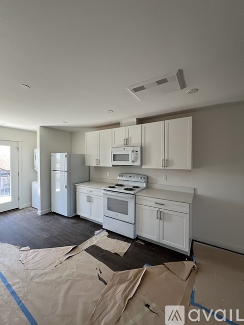 A kitchen with white cabinets and appliances is under construction.