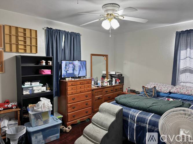 A bedroom with a bed, dresser, and a ceiling fan.