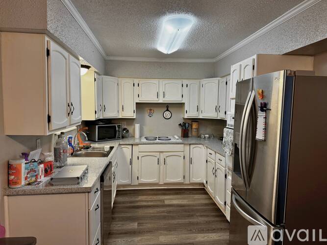 A kitchen with white cabinets and a stainless steel refrigerator.