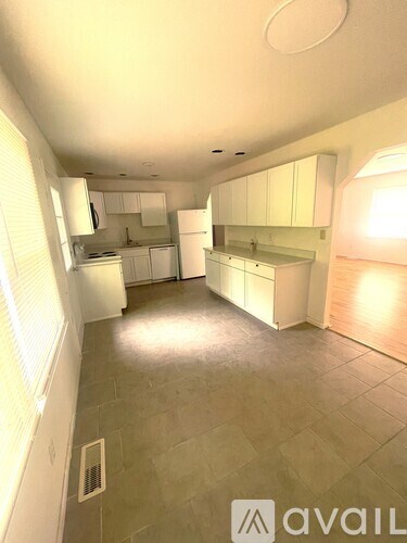 A kitchen with white cabinets and a tiled floor.