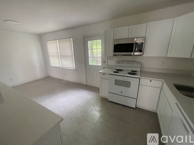 A kitchen with white cabinets and a tiled floor.