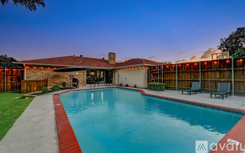 A backyard with a pool and patio furniture.