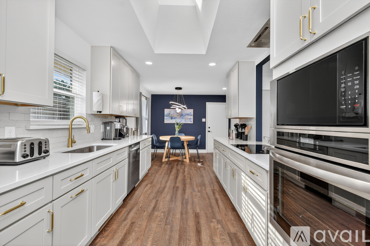 A modern kitchen with white cabinets and a wooden floor.