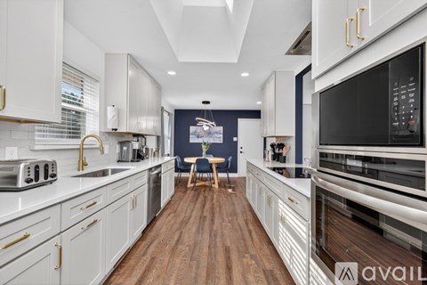 A modern kitchen with white cabinets and a wooden floor.