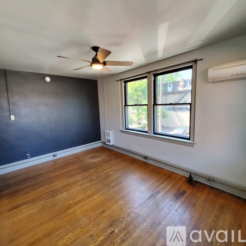 A room with a ceiling fan and wooden flooring.