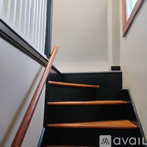 A staircase with a black handrail and wooden steps.