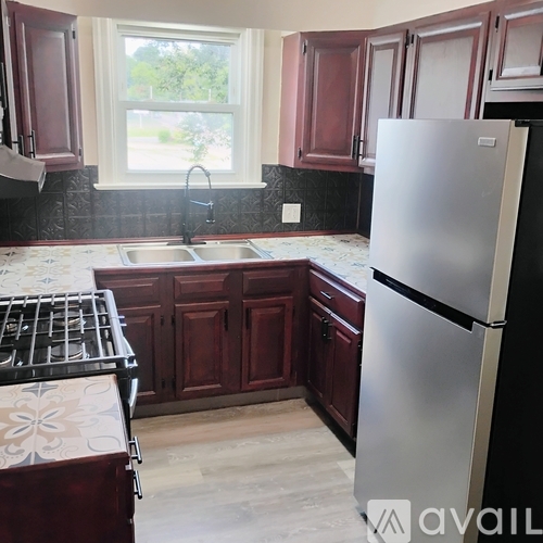 A kitchen with a refrigerator, sink, and stove.