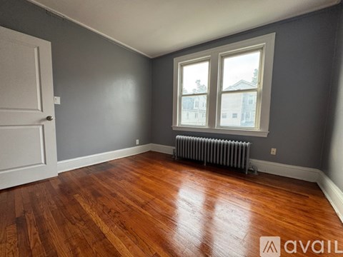 A room with a wooden floor and a window with a view of buildings outside.