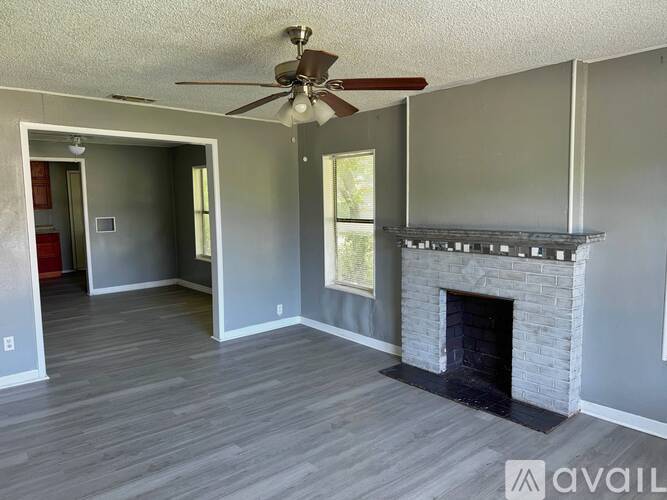 A living room with a fireplace and a ceiling fan.