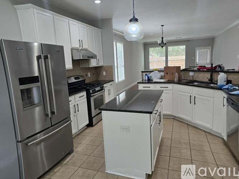 A kitchen with white cabinets and a black countertop.