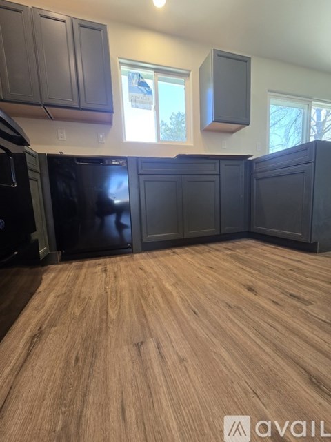 A kitchen with black cabinets and a wooden floor.