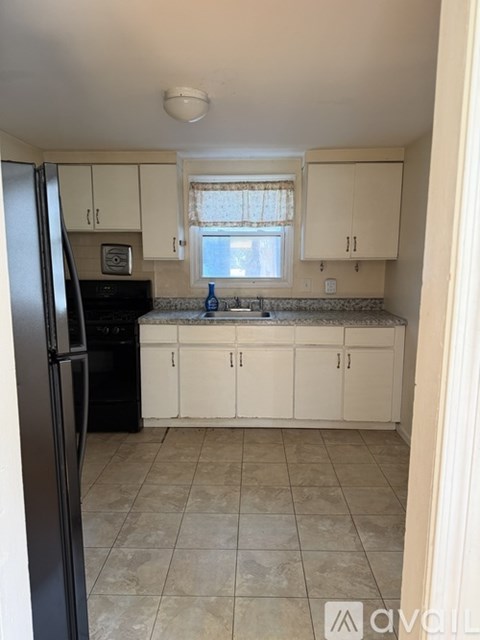 A kitchen with white cabinets and a black fridge.
