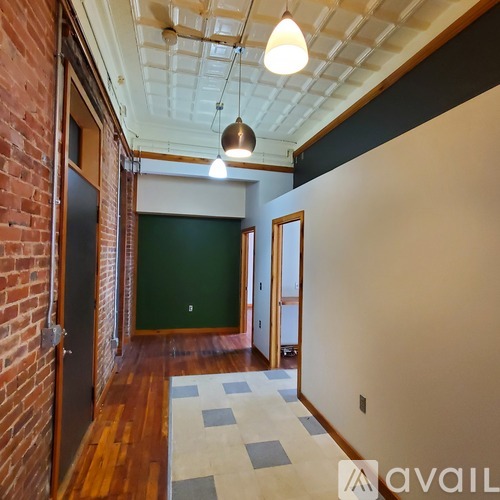 A hallway with a brick wall on the left and a green wall in the distance.