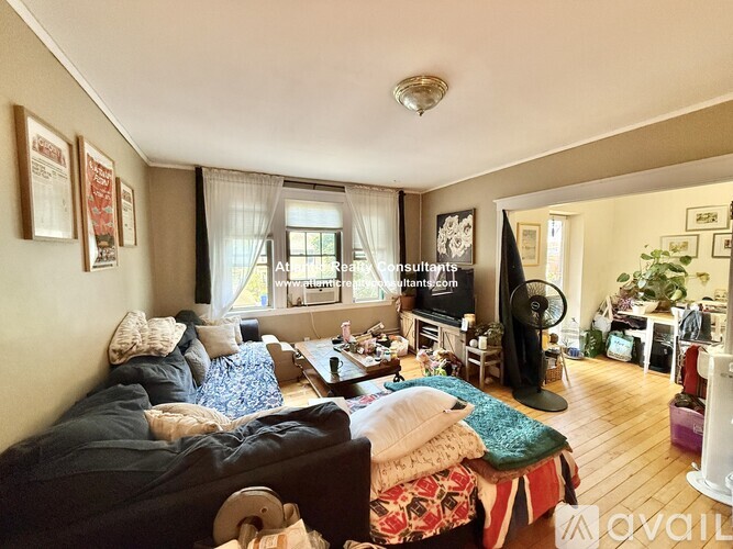 A living room with a couch, a fan, and a television.