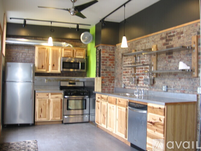 A kitchen with wooden cabinets and a brick wall.