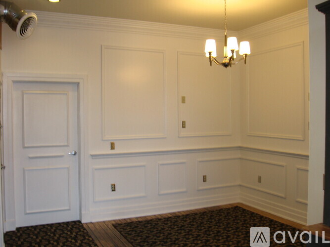 A room with a door, a chandelier and a wall.