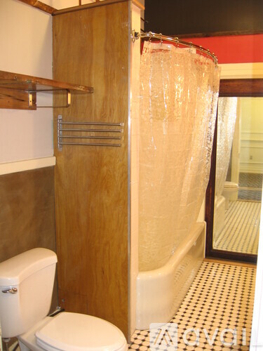 A white toilet sits next to a wooden cabinet in a bathroom.