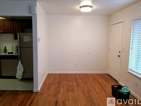 A kitchen with a refrigerator and wooden floors.