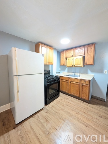 A kitchen with a white refrigerator, wooden cabinets, and a black stove top oven.
