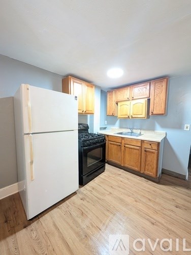 A kitchen with a white refrigerator, wooden cabinets, and a black stove top oven.