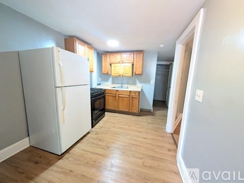 A kitchen with a white fridge and wooden cabinets.
