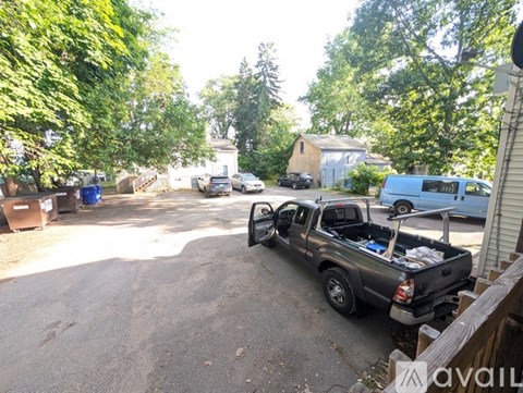 A truck is parked in a driveway with trees and a house in the background.