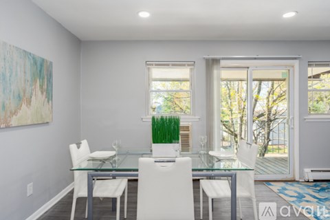 A dining room with a glass table and white chairs.
