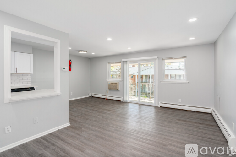A spacious room with wooden flooring and white walls.