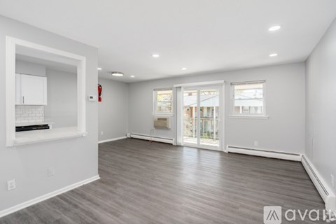 A spacious room with wooden flooring and white walls.