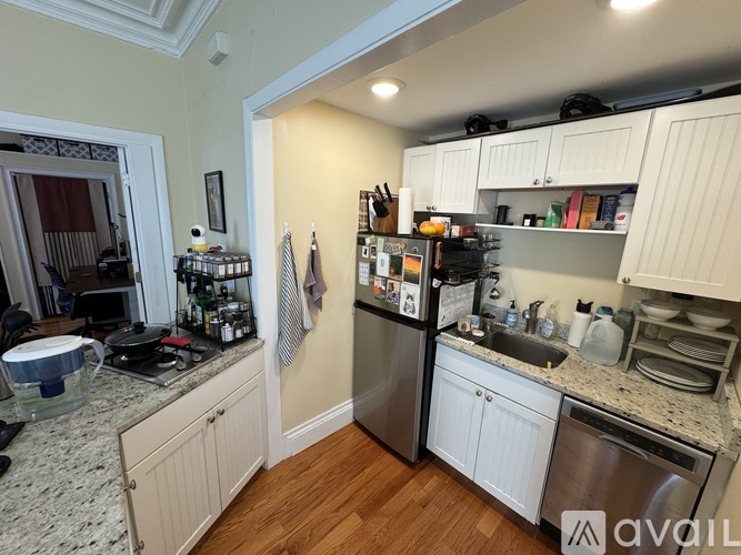 A kitchen with a refrigerator, sink, and cabinets.