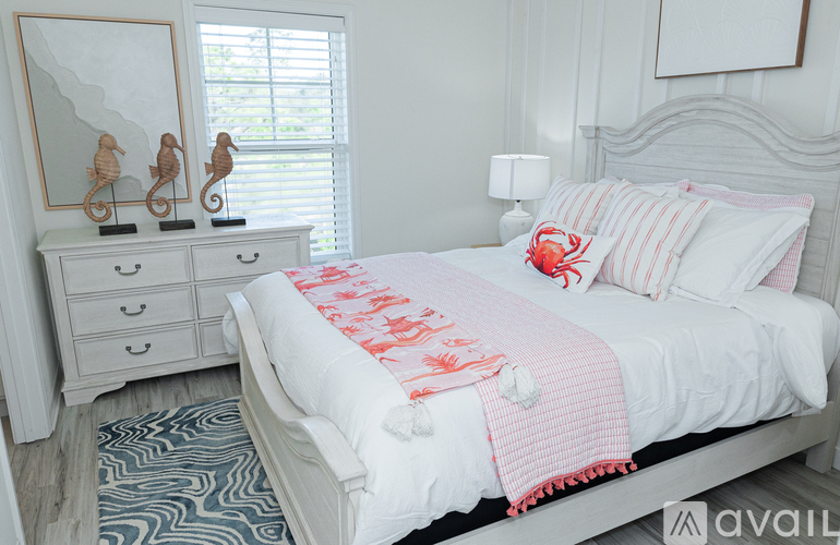A bedroom with a bed, nightstand, and a dresser with two seahorse figurines on top.