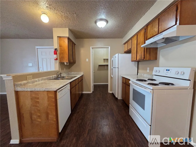 A kitchen with white appliances and wooden cabinets.