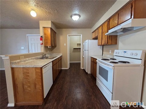 A kitchen with white appliances and wooden cabinets.
