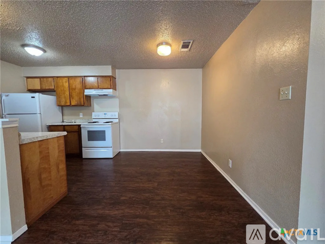 A kitchen with white appliances and wooden cabinets.