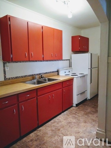 A kitchen with red cabinets and a white refrigerator.