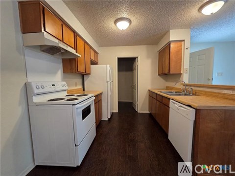 A kitchen with white appliances and wooden cabinets.