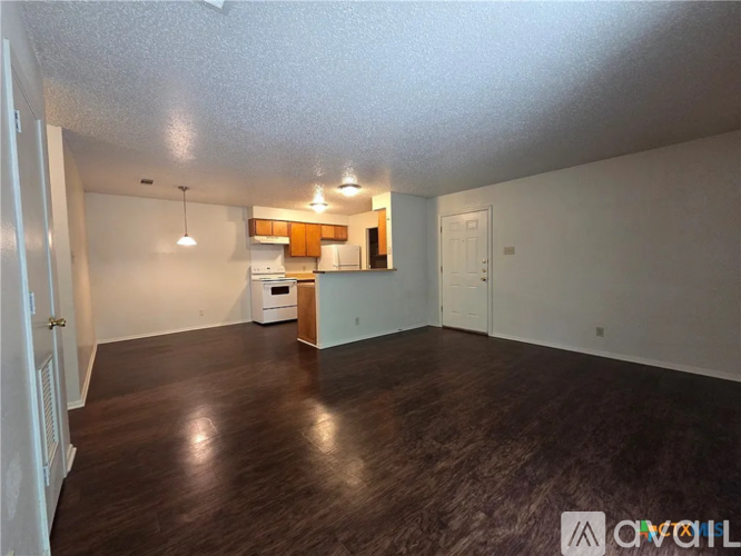 A spacious room with wooden flooring and a small kitchenette in the corner.